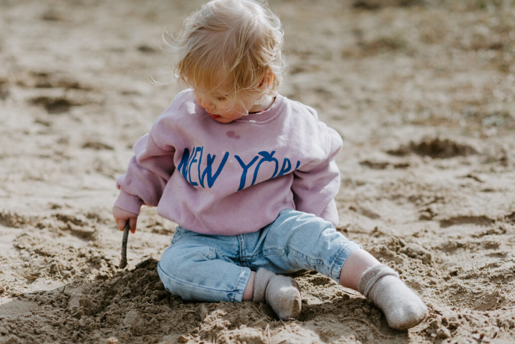 Dreumes speelt lekker in het zand met een takje in de Soesterduinen in het voorjaar.