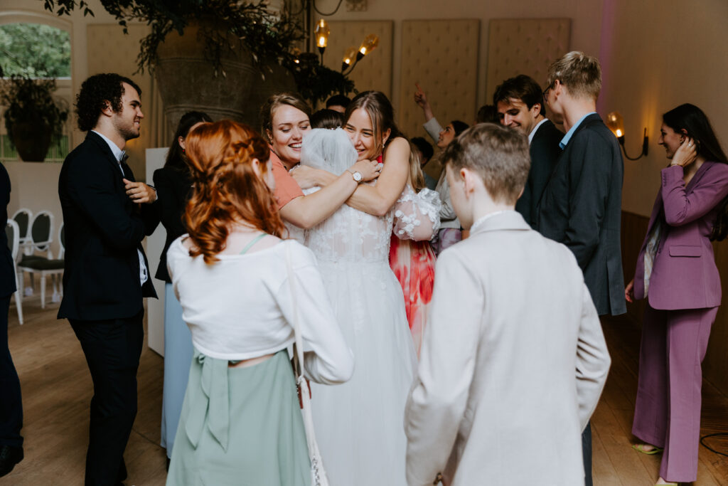 Bruid wordt geknuffeld door vriendinnen na de ceremonie tijdens bruiloft